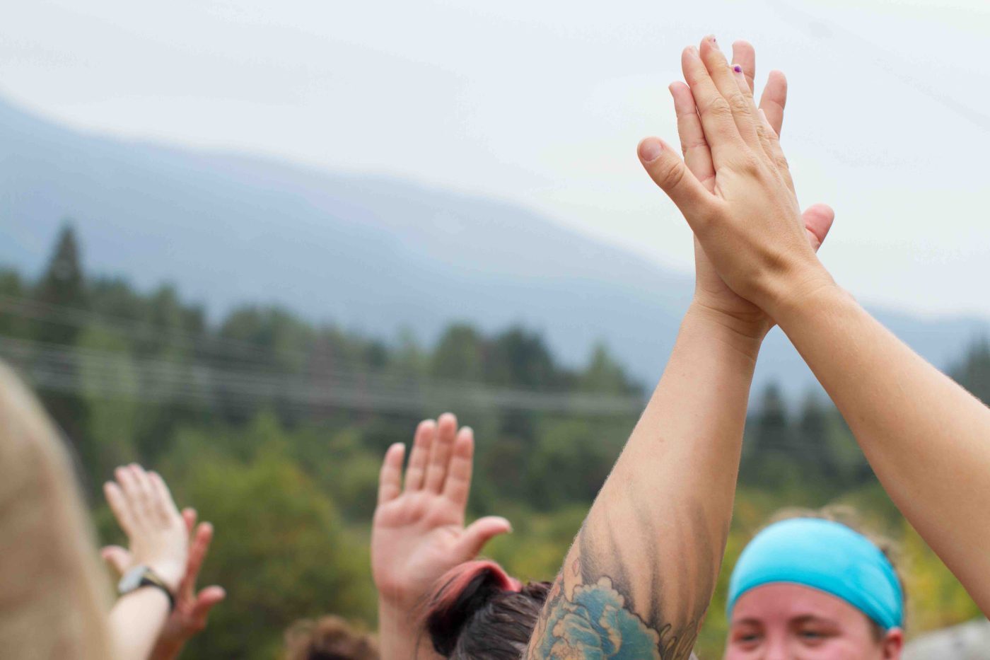 women in a fitness class outside in view of mountains doing a high five